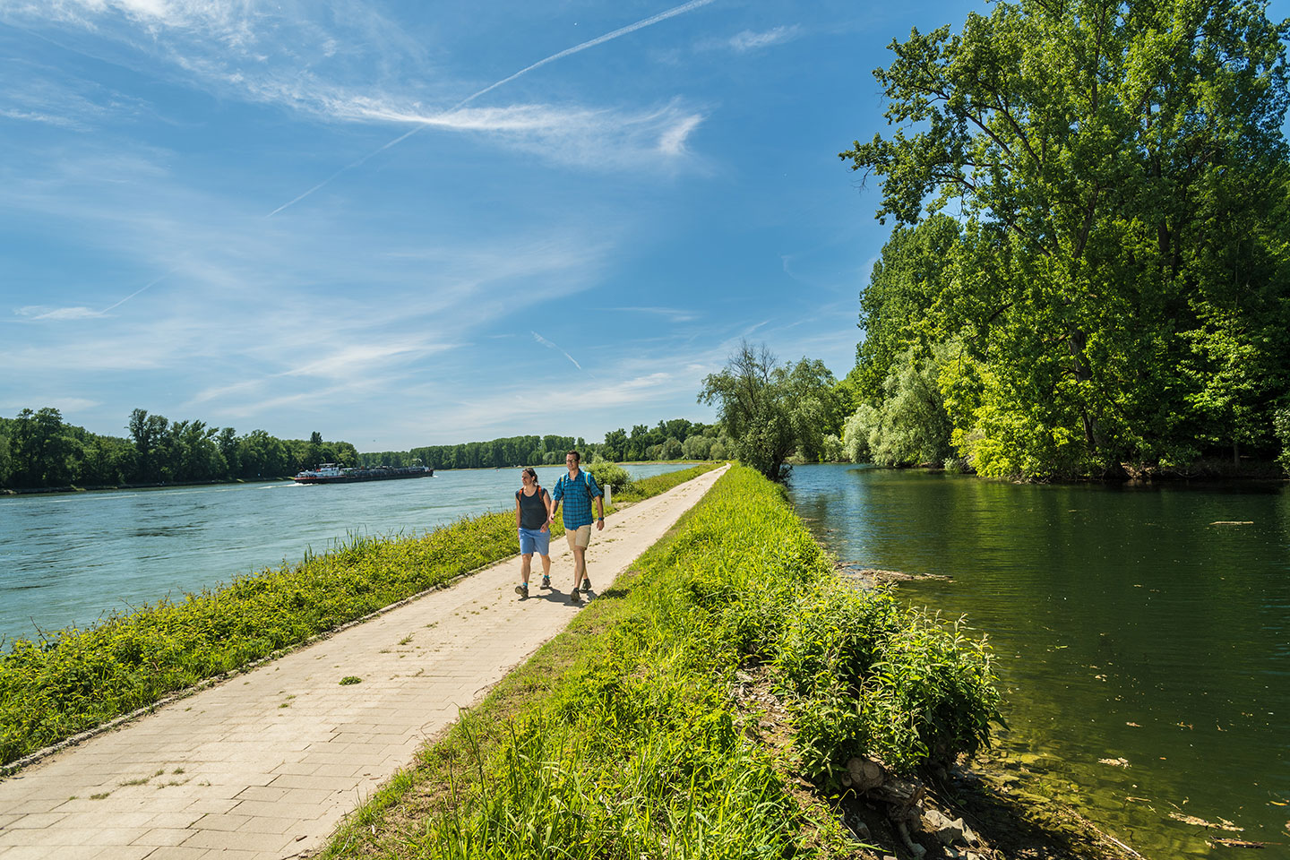 Zwei Wanderer auf dem Treidlerweg, der Weg geht zwischen zwei Seen