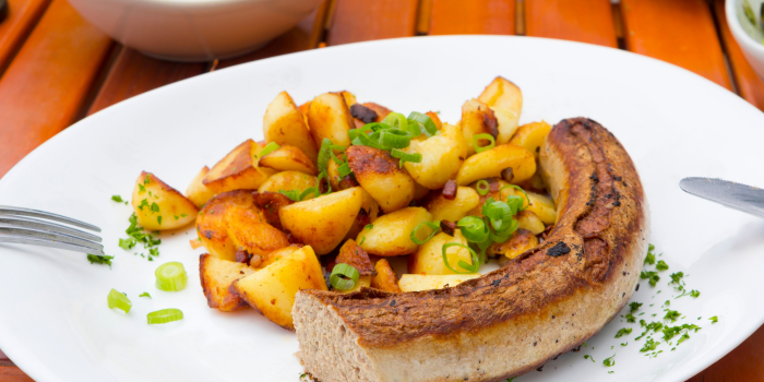 Ein Teller mit Bratwurst und Bratkartoffeln